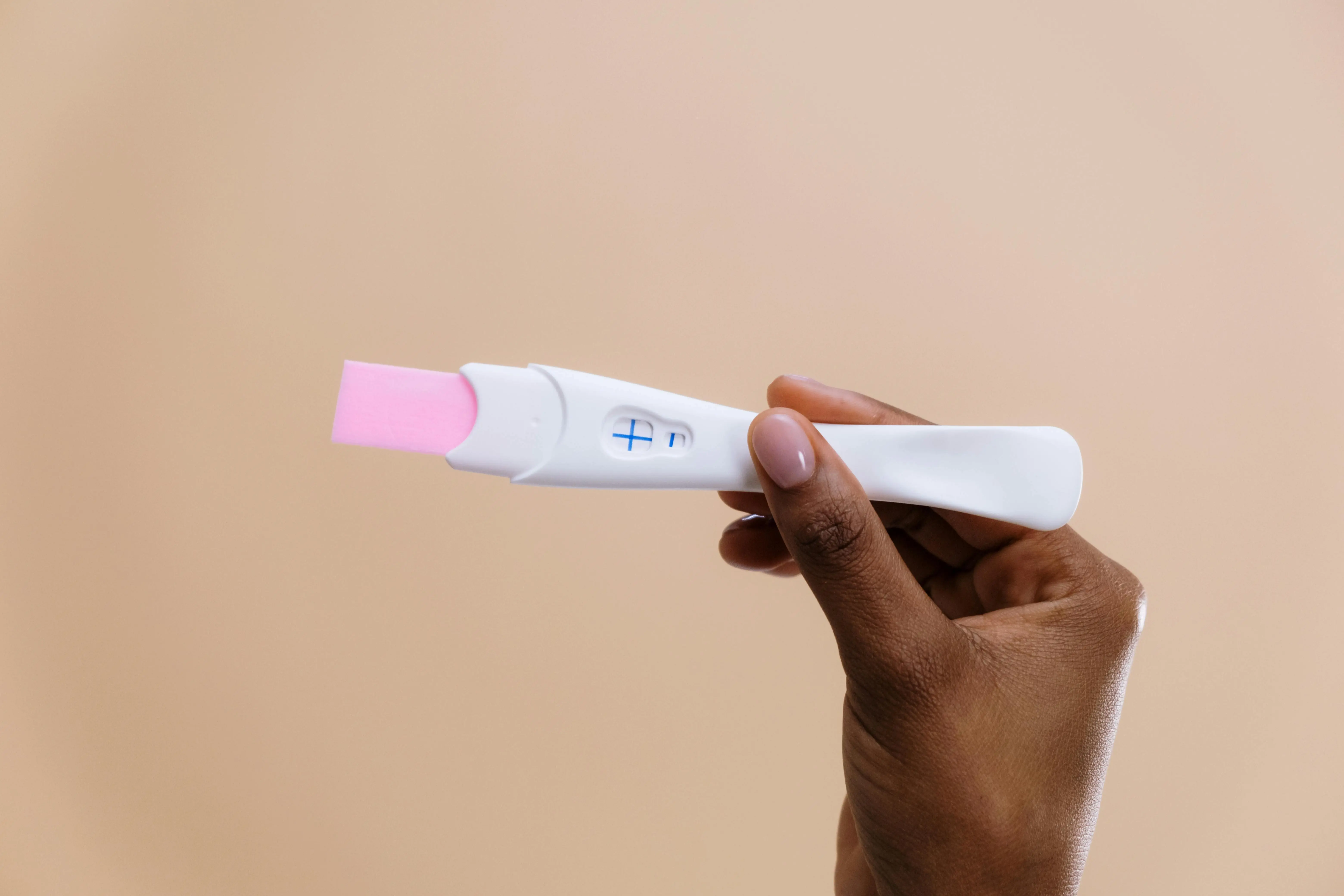 photo of person holding positive pregnancy test in their hand