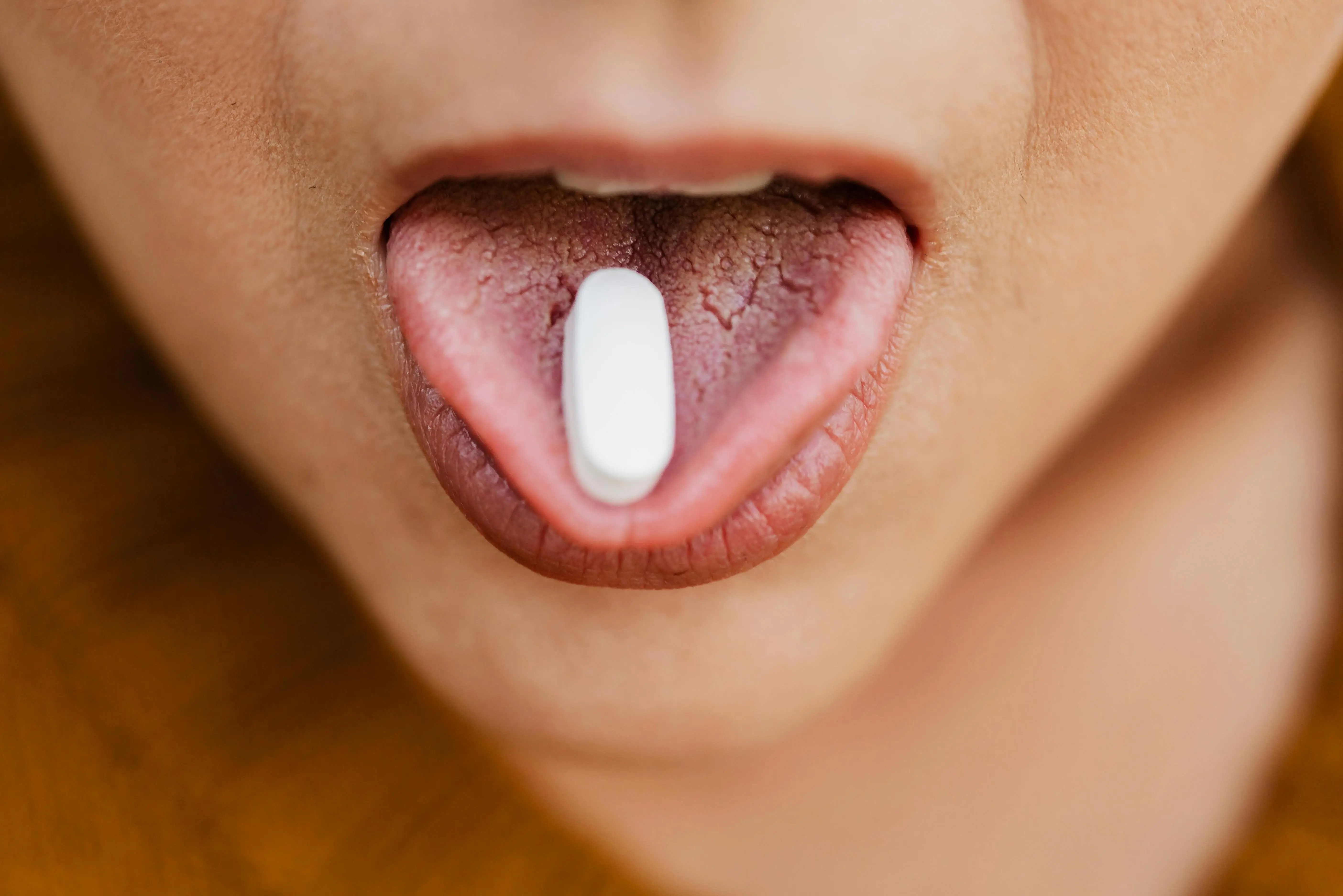 close up photo of person with a pill on their tongue