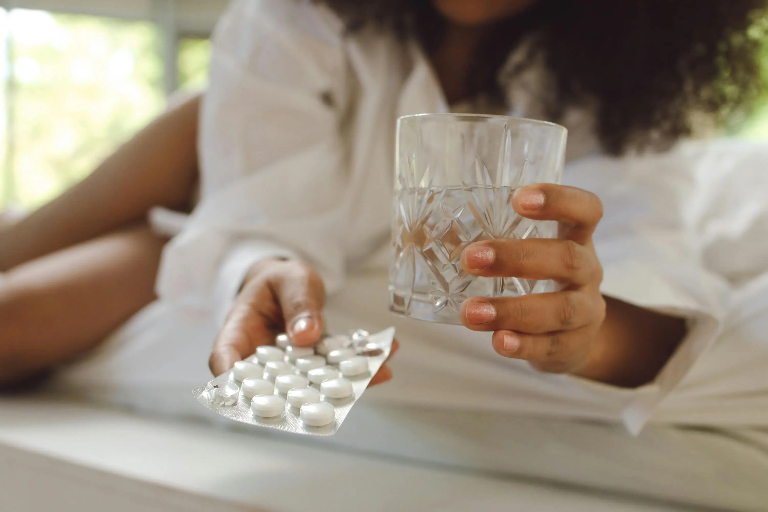 photo of woman reaching for pills and a glass of water