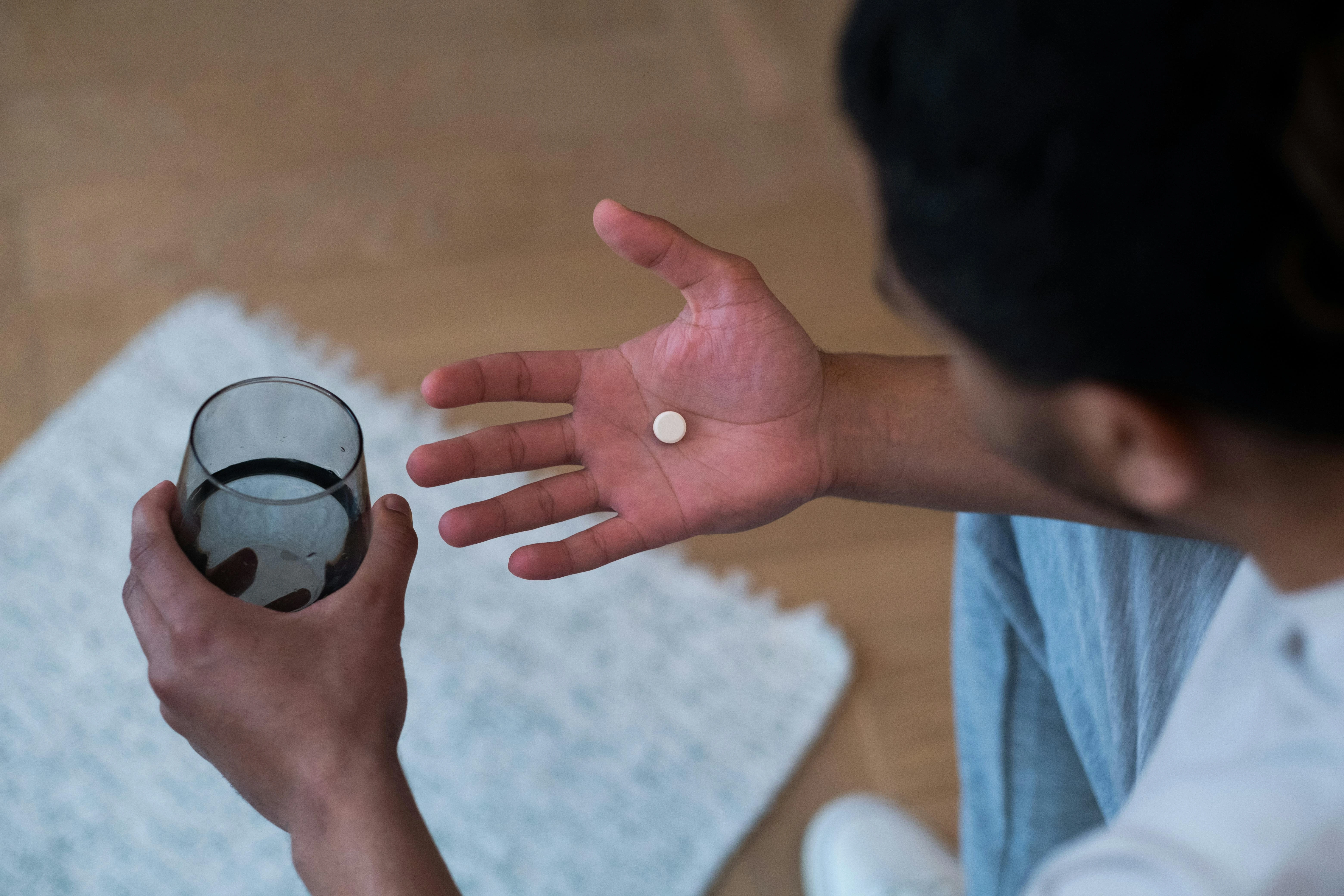 image of a person taking medication with a glass of water