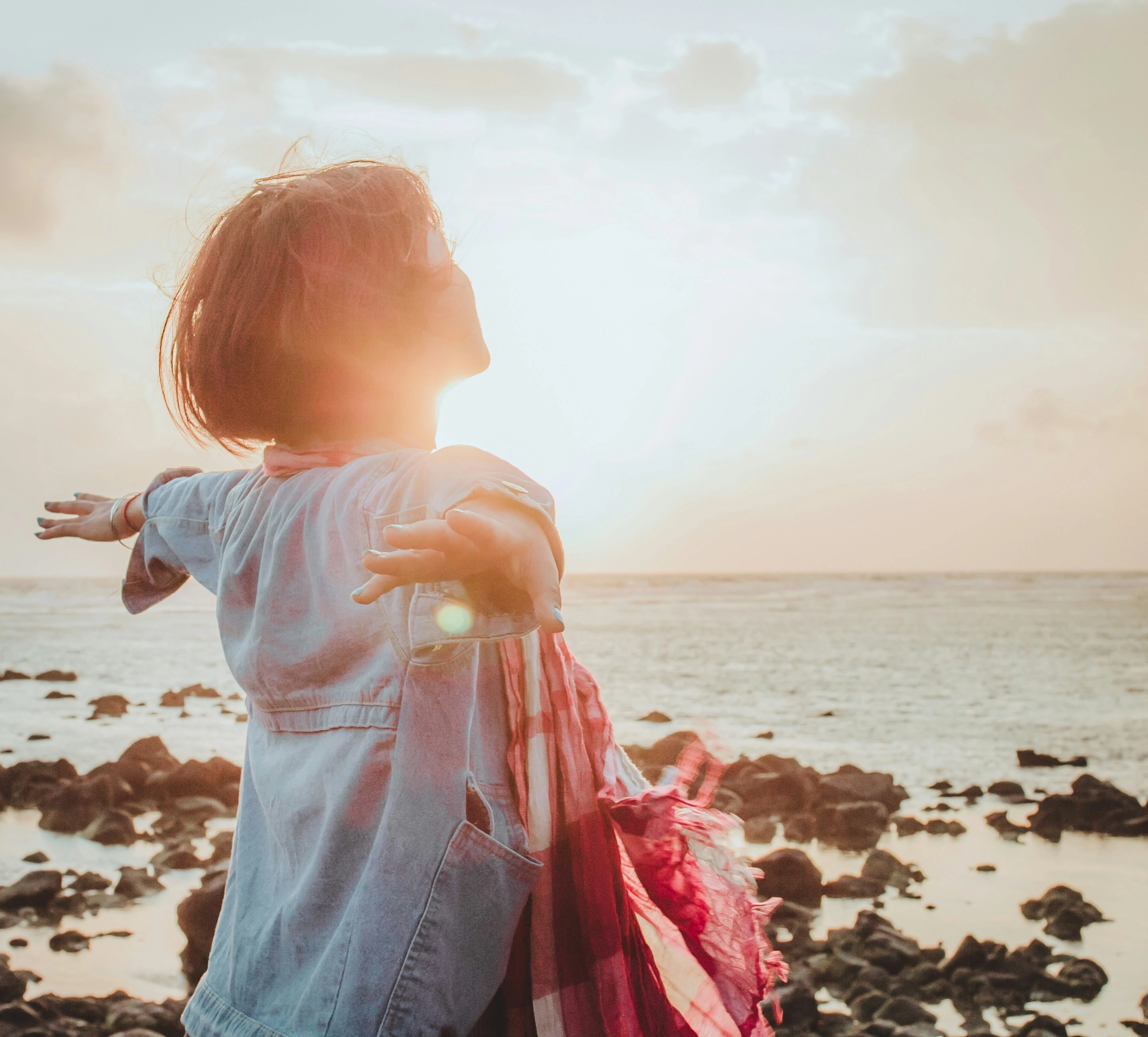photo of person joyfully spreading arms at the beach