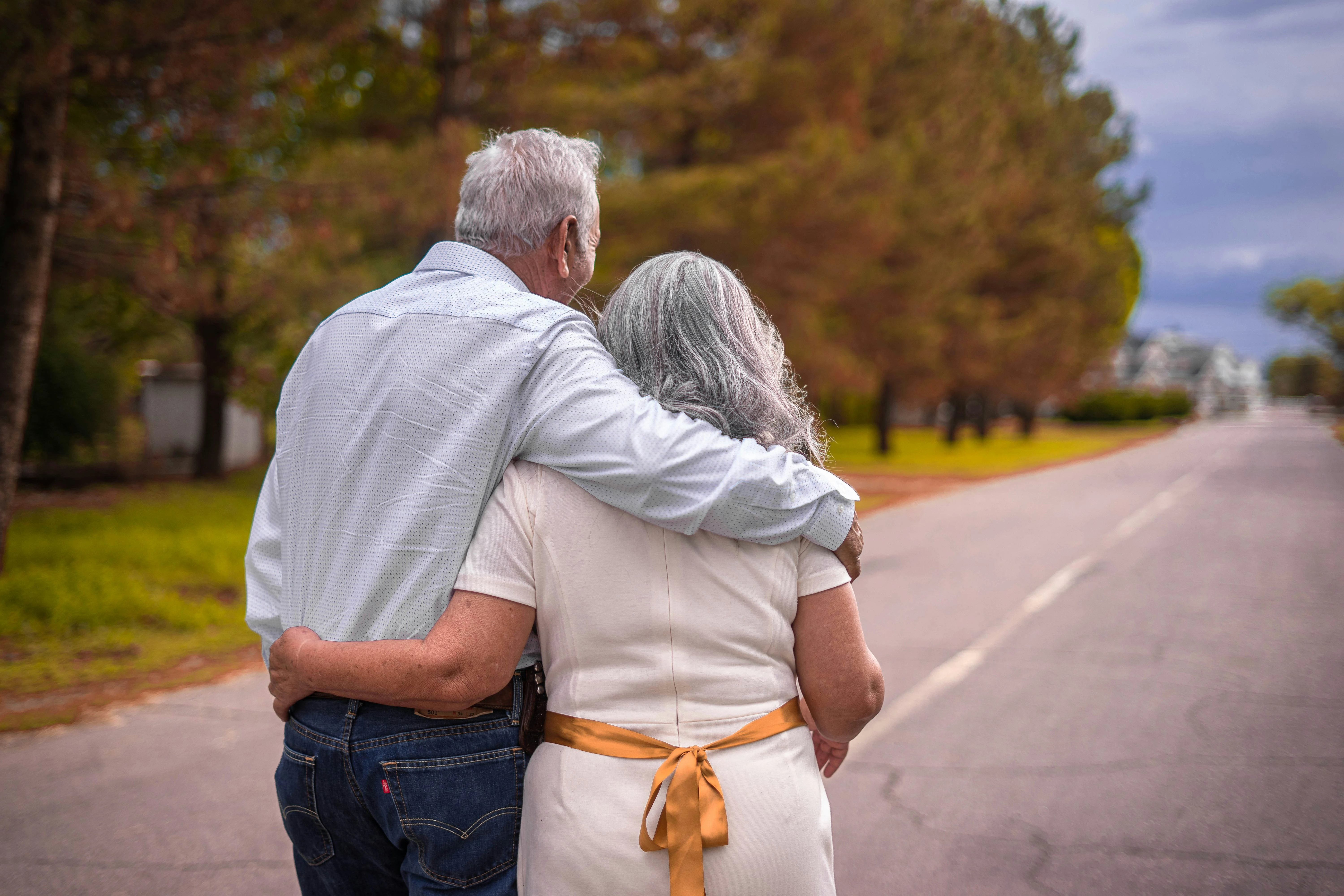 photo of an older couple walking arm in arm down a country road