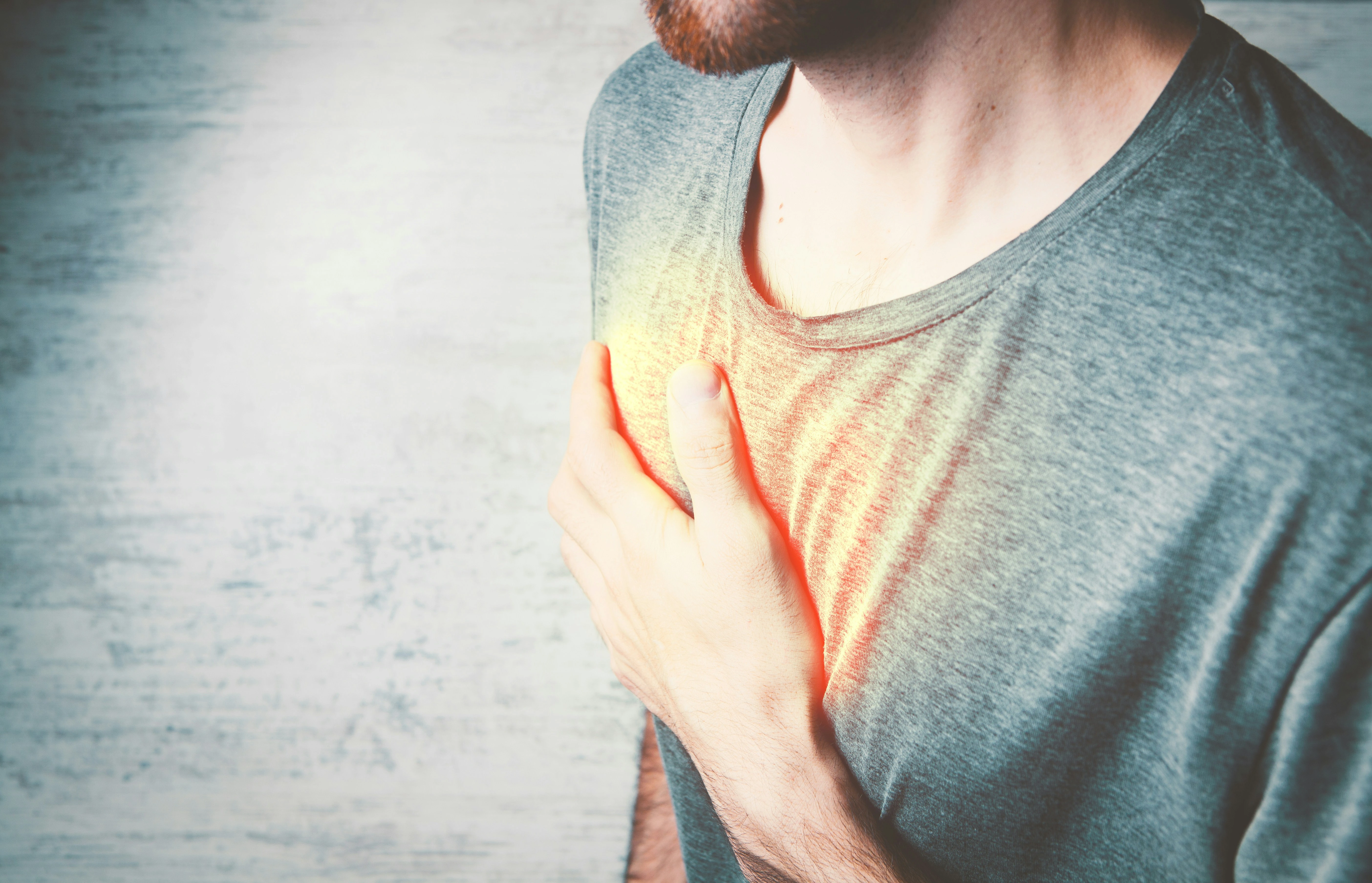 photo of a man holding his chest during an acid reflux flare up